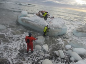 Så måtte varene bæres fra isflaket, gjennom sjø, issørpe og store isklumper til land og opp på landkalven. Foto: Tom Erik Glomsrud