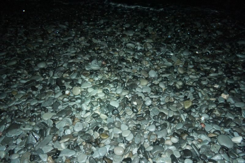 Puslespill av isglassert småstein på stranda.